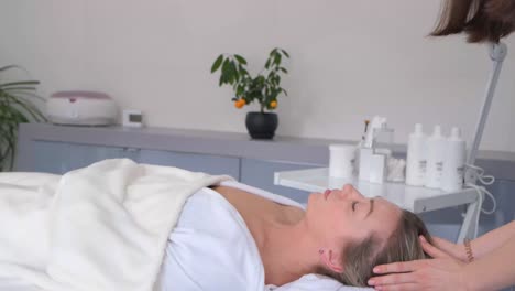 a beautiful woman is lying on a couch at a reception by a beautician. the doctor makes beauty injections to the lips. vertical video