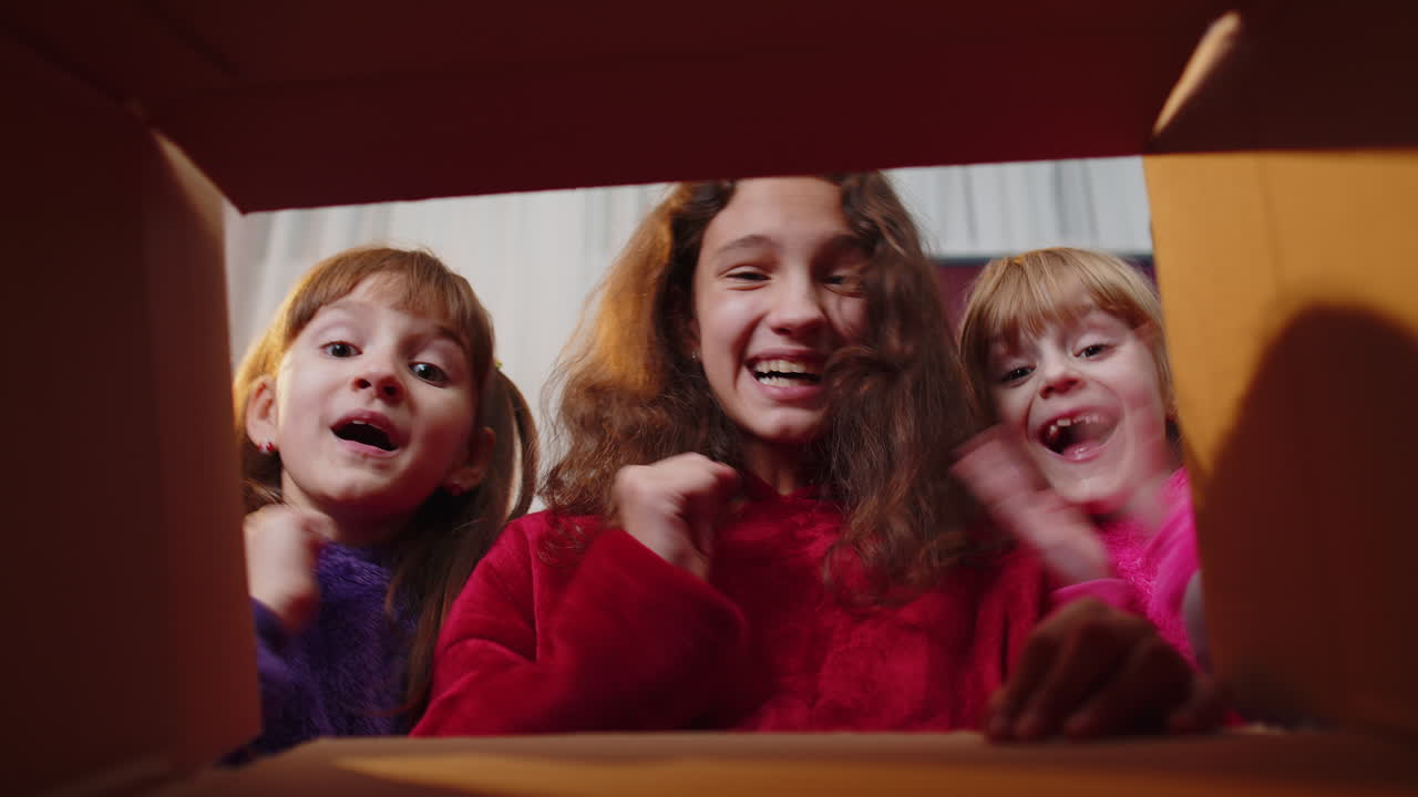 tres hermanos niños niñas desempaquetando paquete de entrega en casa, dentro de la caja de regalo de cartón