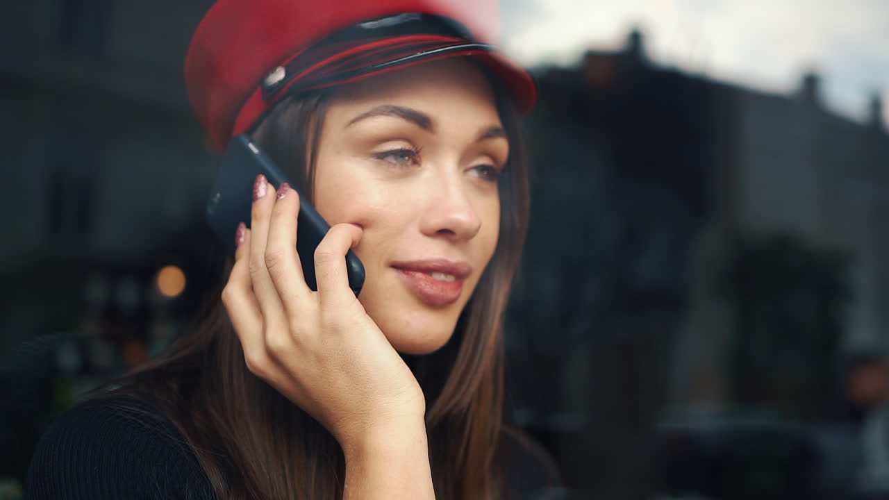A woman with a beret is talking on her cellphone indoors