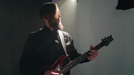 guitarist in black attire deftly plays a red electric guitar, rhythmically moving against a stark white background with smooth camera zooms