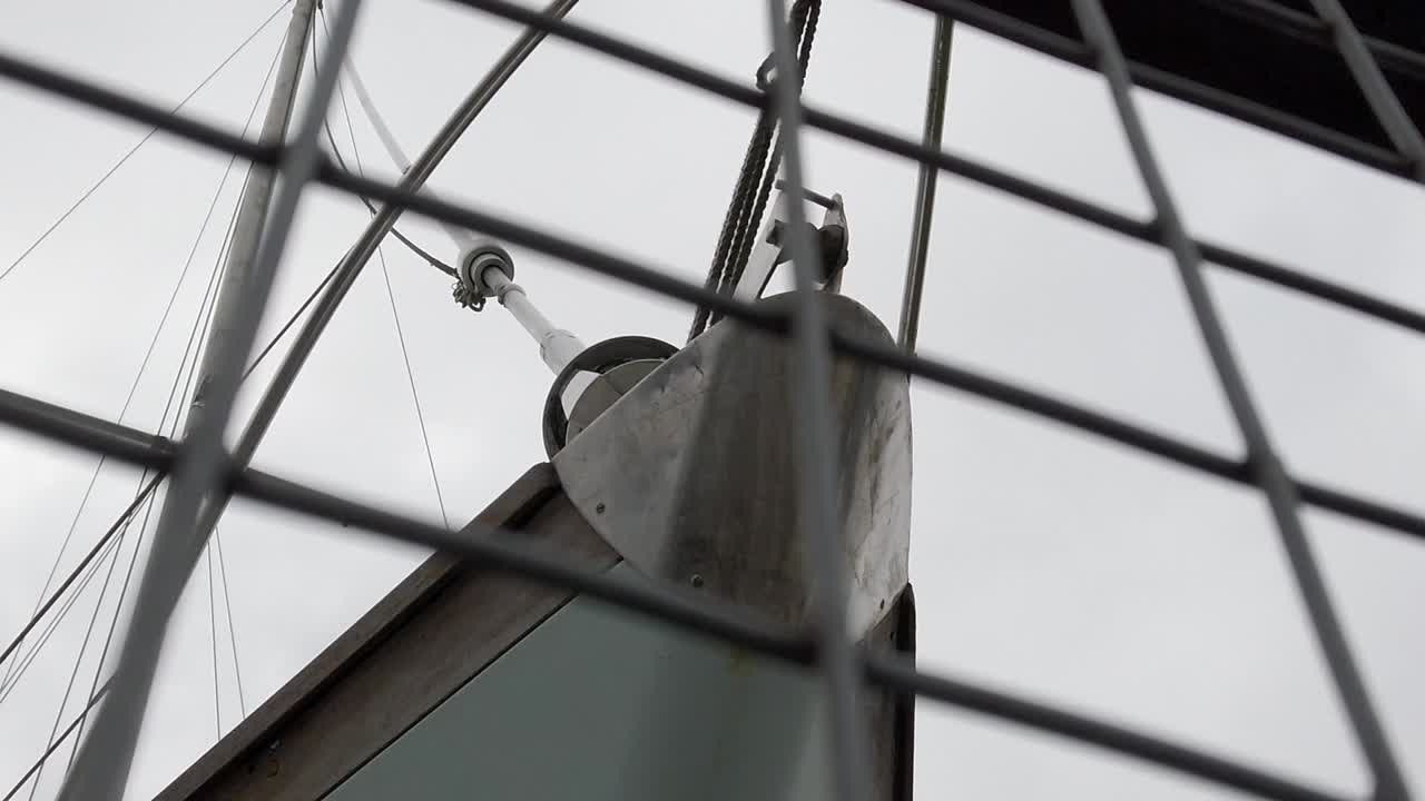 под носом парусного судна за огражденной металлической сеткой верфью тележкой слева