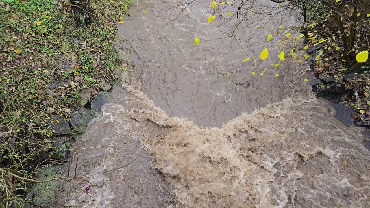 Flooded river and powerful waterfall after extreme rain in slow motion