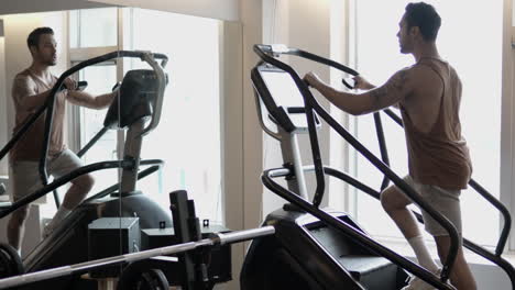 silhouetted man walking up on stepmill machine at indoor gym to burn calories