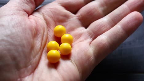 yellow dragees from jar in hand closeup