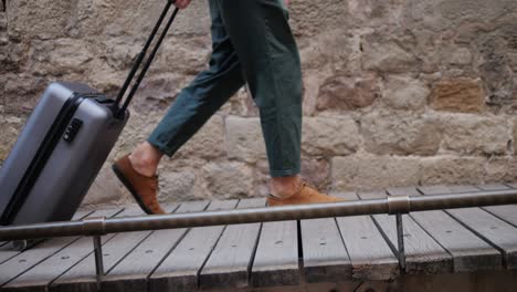 man walking with luggage on a wooden bridge