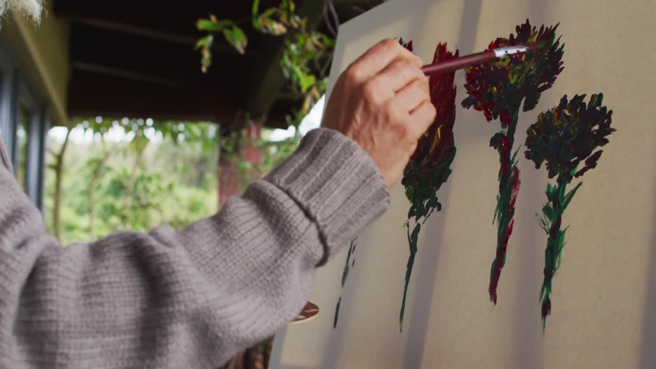 Senior mixed race woman painting on balcony