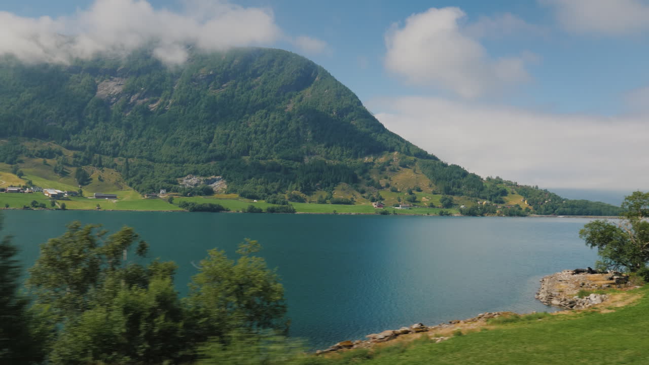 la orilla del fiordo la cima de las montañas se están ahogando en las nubes vista desde la ventana de t