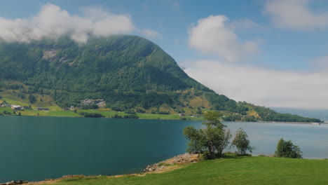 the shore of the fjord the top of the mountains are drowning in the clouds view from the window of t