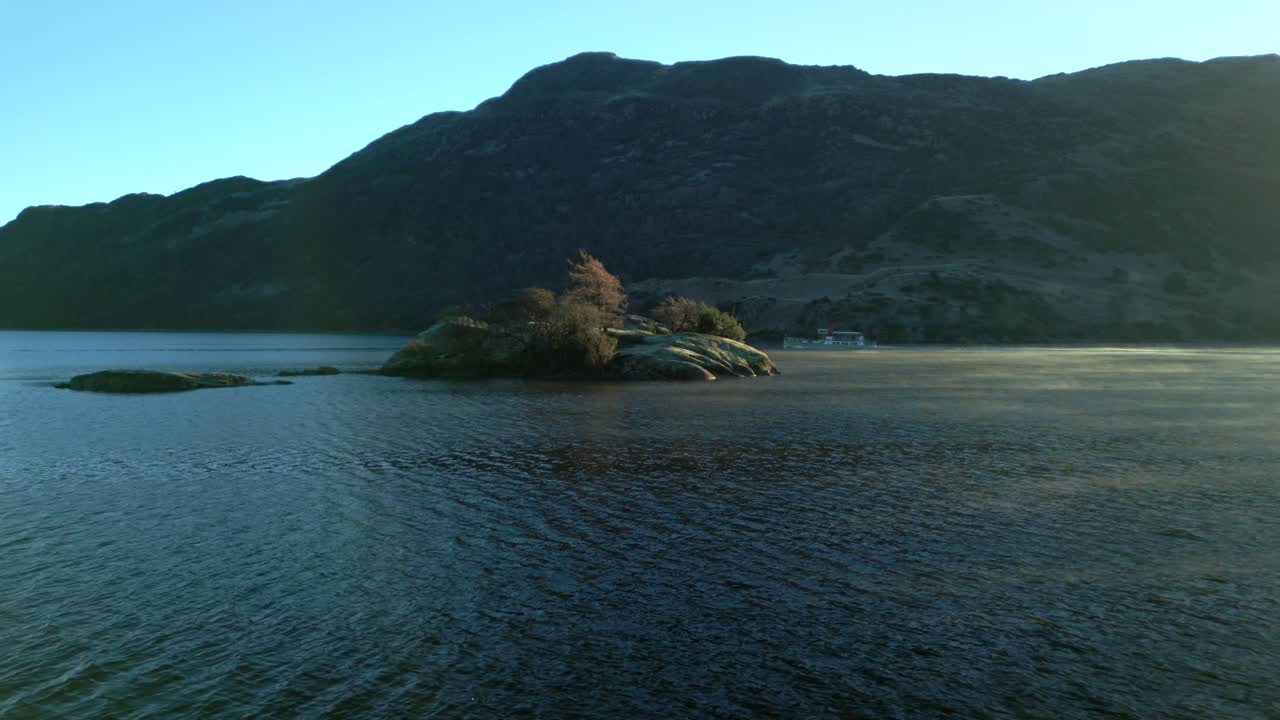 보트는 가을에 해가 뜨면 안개가 굴러가면서 조용한 호수에서 작은 섬 뒤로 움직입니다.