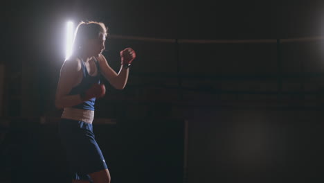 Boxer-woman-in-red-bandages-on-the-hands-of-and-blue-t-shirt-conducts-battle-with-of-practicing-the-speed-and-technique-strikes-hands.-Camera-movement-side-View.-Steadicam-shot