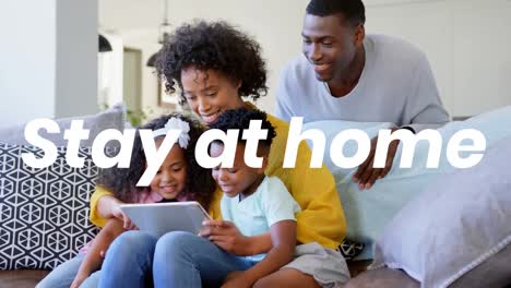 Animation-of-stay-at-home-text-over-parents-with-sister-and-brother-using-tablet-at-home