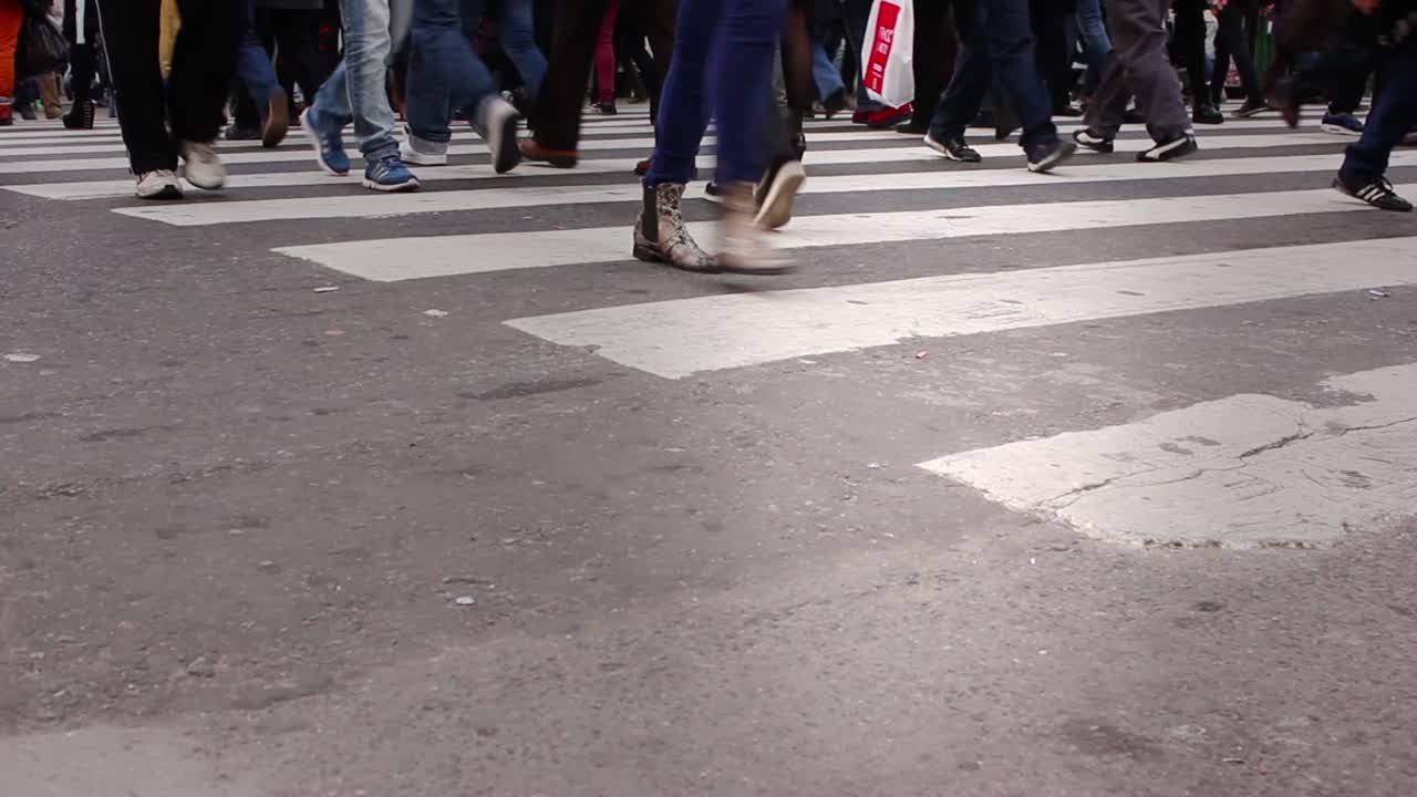 Vista en ángulo bajo de peatones cruzando un concurrido paso de cebra de la ciudad