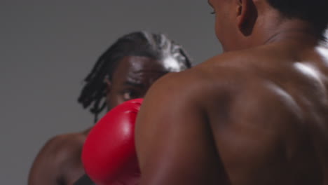 Close-Up-Studio-Shot-Of-Two-Male-Boxers-Wearing-Gloves-Fighting-In-Boxing-Match-Against-Grey-Background-6