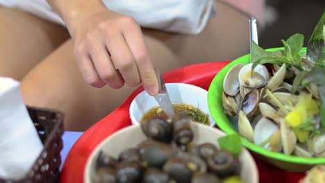 persona sumergiendo caracoles en una salsa salada