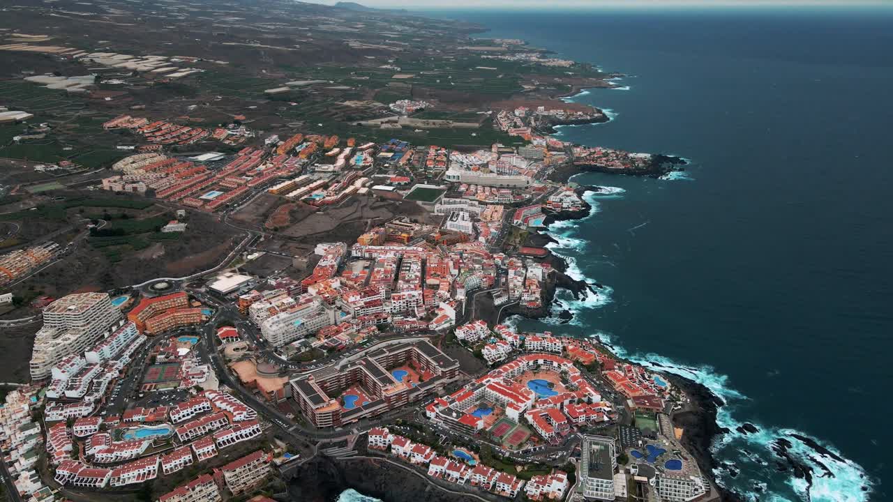 Aerial Dolly Away From Large Costal City in Tenerife Spain, Orange Buildings, Sea