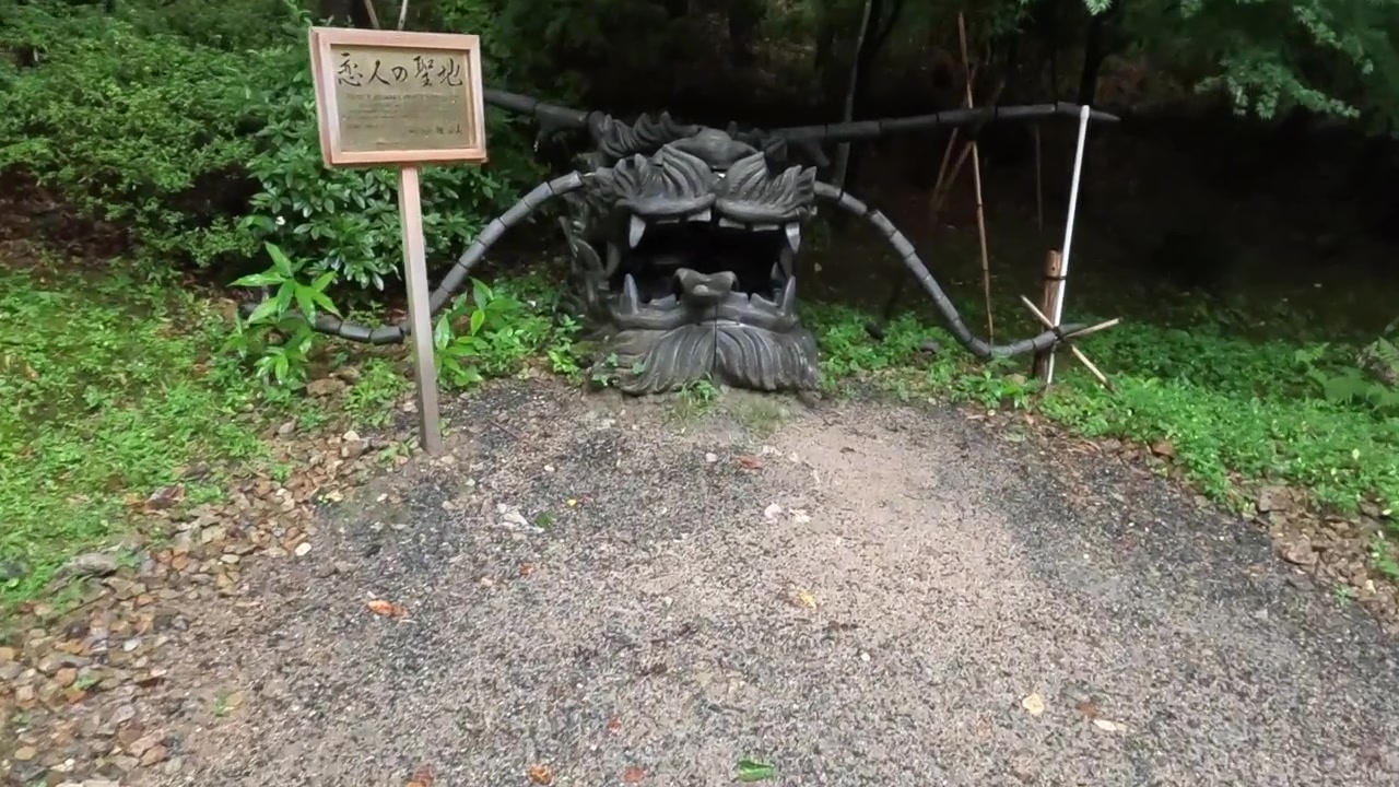 Aproximando-se de uma fonte em forma de dragão em um tranquilo jardim de Quioto com vegetação exuberante.