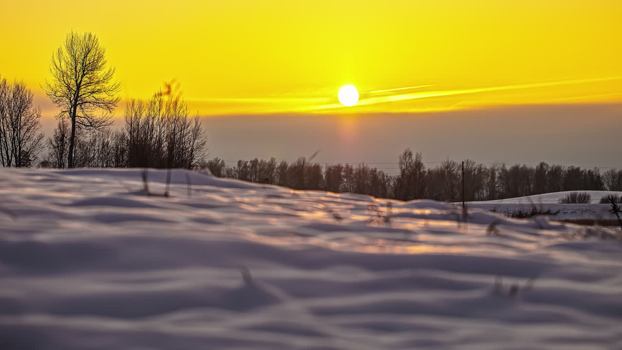 눈 덮인 풍경 위에 노란 하늘로 지는 태양의 지상 시간 경과