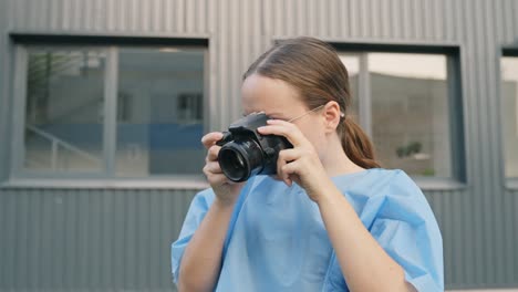 young woman in scrub takes pictures using digital camera