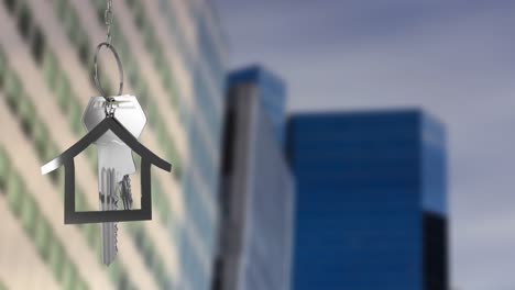 Animation-of-hanging-silver-house-keys-against-blurred-view-of-tall-buildings