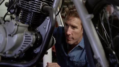 male mechanic repairing motorbike in repair garage 4k