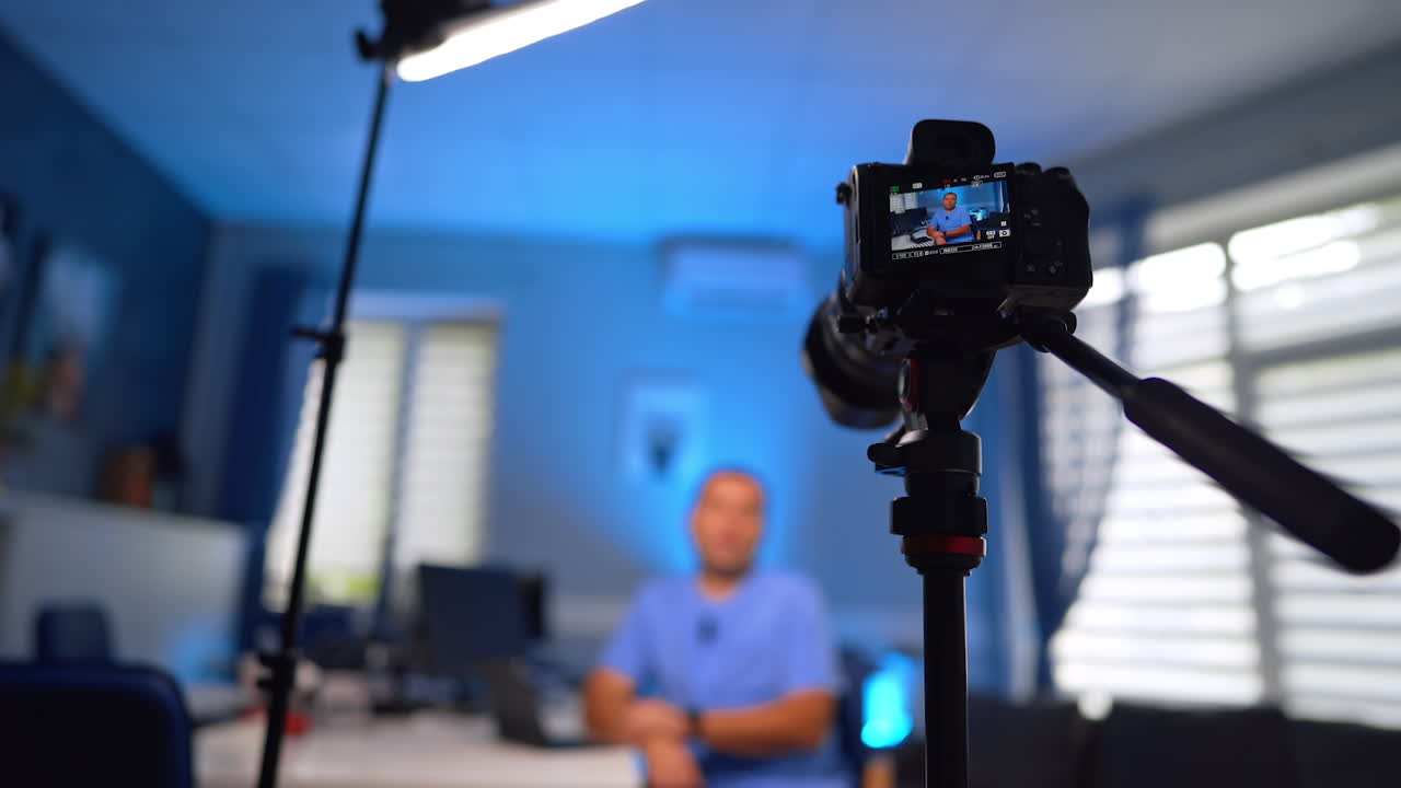 Working camera records a man recording a video. Medic in blue uniform talks for medical content. Low angle view. Selective focus