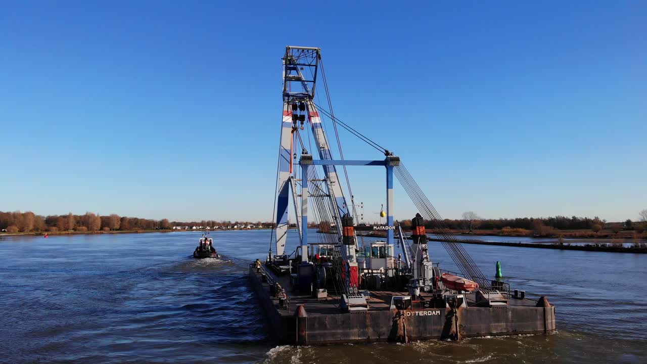 gran sheerleg flotante tirado por un remolcador en el río durante el día cerca de barendrecht, países bajos