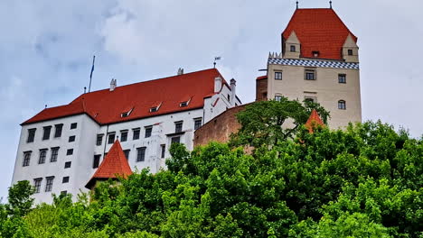 closeup view of trausnitz castle and tower with steep red roof above green treetops
