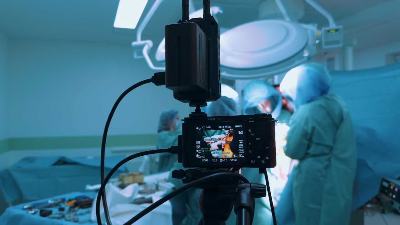 Kyiv, Ukraine, 2 August 2025: Camera recording a surgical procedure, focusing on the screen and wireless transmitter. The device captures the surgeons working blurred in the background under bright operating lights