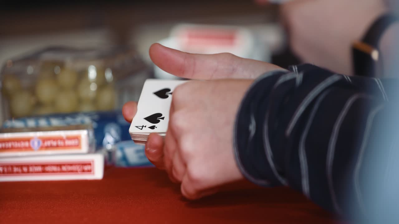 Close up of a pair of hands playing with a deck of cards, flips one card around and puts it back. 4k.