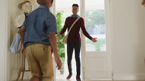 happy african american son welcoming and embracing father coming home