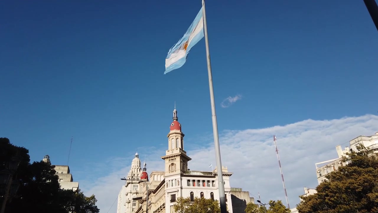 Argentina Flag Wave Above Palacio Barolo and Buenos Aires Skyline at Plaza Congreso Low Angle View