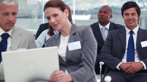 People-using-a-laptop-while-a-businessman-looks-at-camera