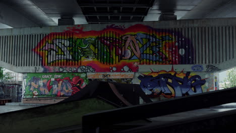 no people at skatepark with colorful graffiti on wall. empty skate park ramp.