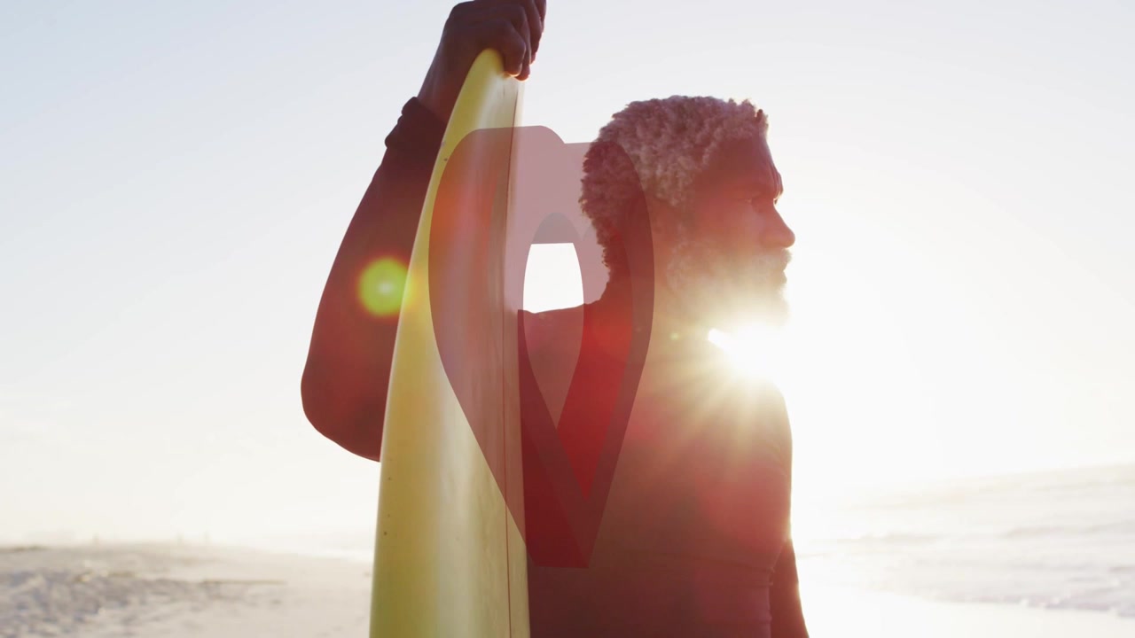 Mature man holding yellow surfboard, preparing surf while sun backlit causing heart overlay pulsing