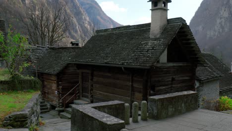 Casas-De-Madera-Con-Chimeneas-De-Piedra-Se-Encuentran-Con-La-Primera-Nevada-En-El-Pueblo-De-Montaña-De-Cavergno,-Suiza