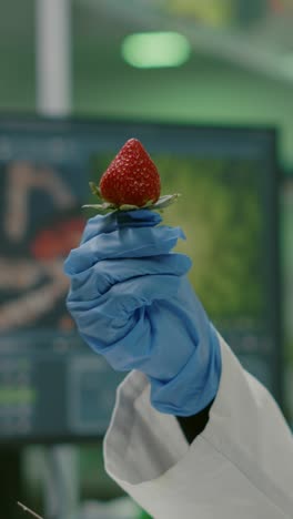 scientist in lab coat injecting a strawberry with a syringe