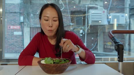 Korean-woman-grilled-pork-salad-from-wooden-bowl,-urban-alley-background