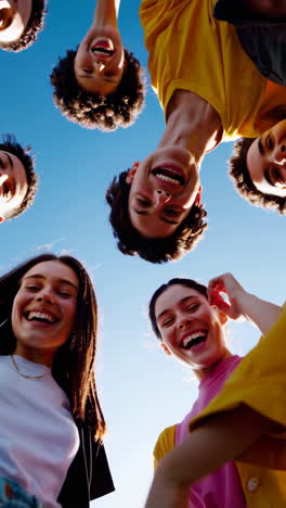 joyful young friends huddling together under a blue sky