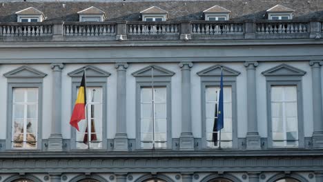 belgian and european union flags waving in the wind on an old building in brussels, belgium