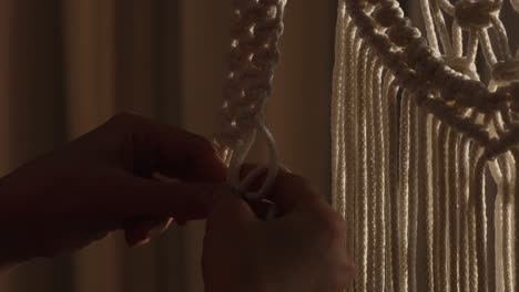 close-up of hands making macrame wall hanging
