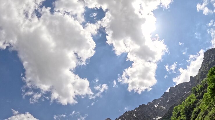 Time-lapse dal basso di soffici nuvole bianche che scorrono in un cielo azzurro soleggiato sopra le montagne