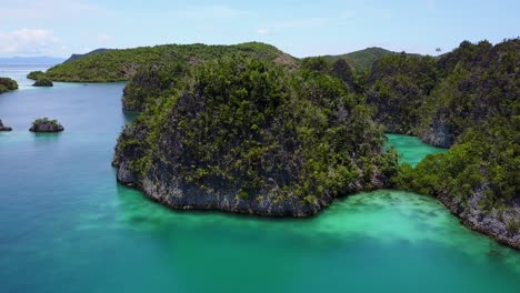 Drone-footage-of-tropical-forest-mountains-and-clear-water-in-Raja-Ampat,-Indonesia