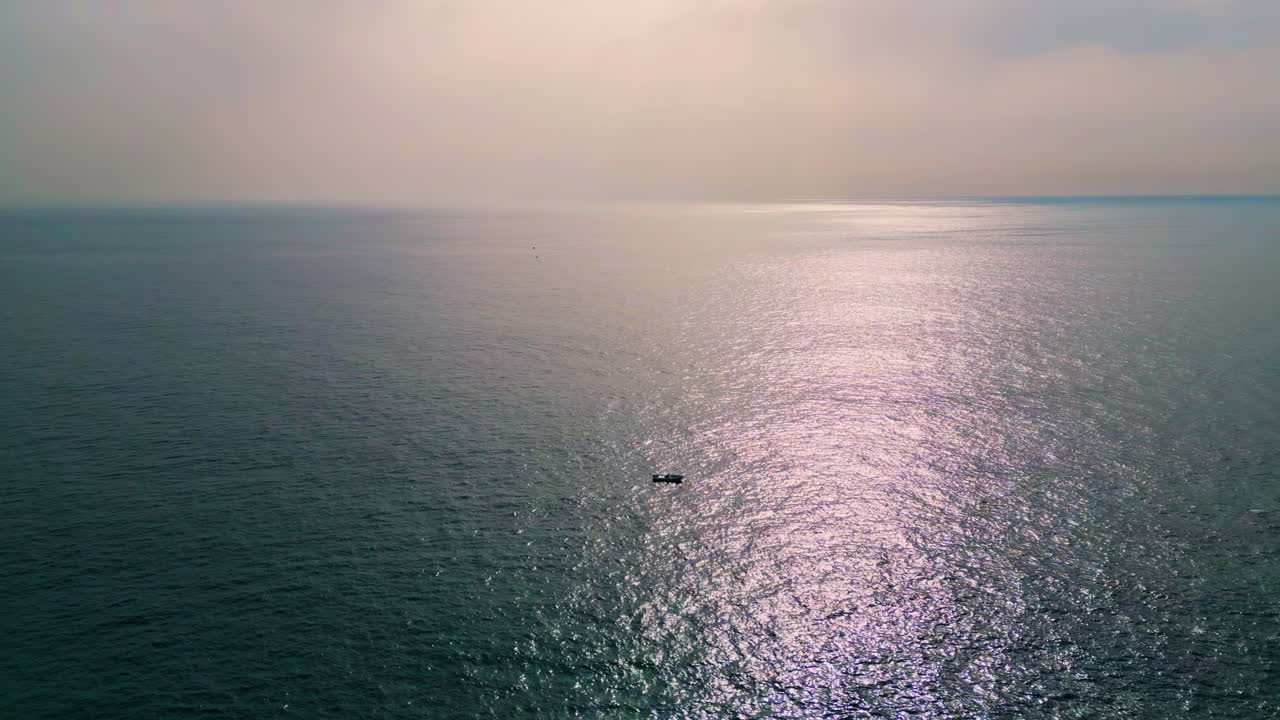끝없는 바다를 떠다니는 외로운 보트. 빛나는 빛이 물을 반사합니다.