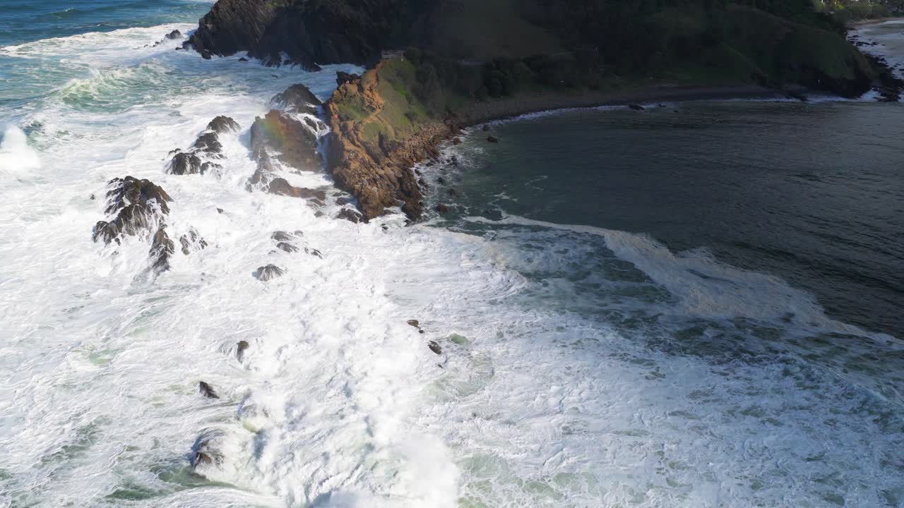 Aerial view of powerful waves crashing against rocky cliffs at Byron Bay, showcasing dynamic ocean movement and natural beauty