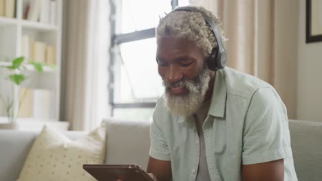 Video-of-african-american-senior-man-using-tablet-and-headphones
