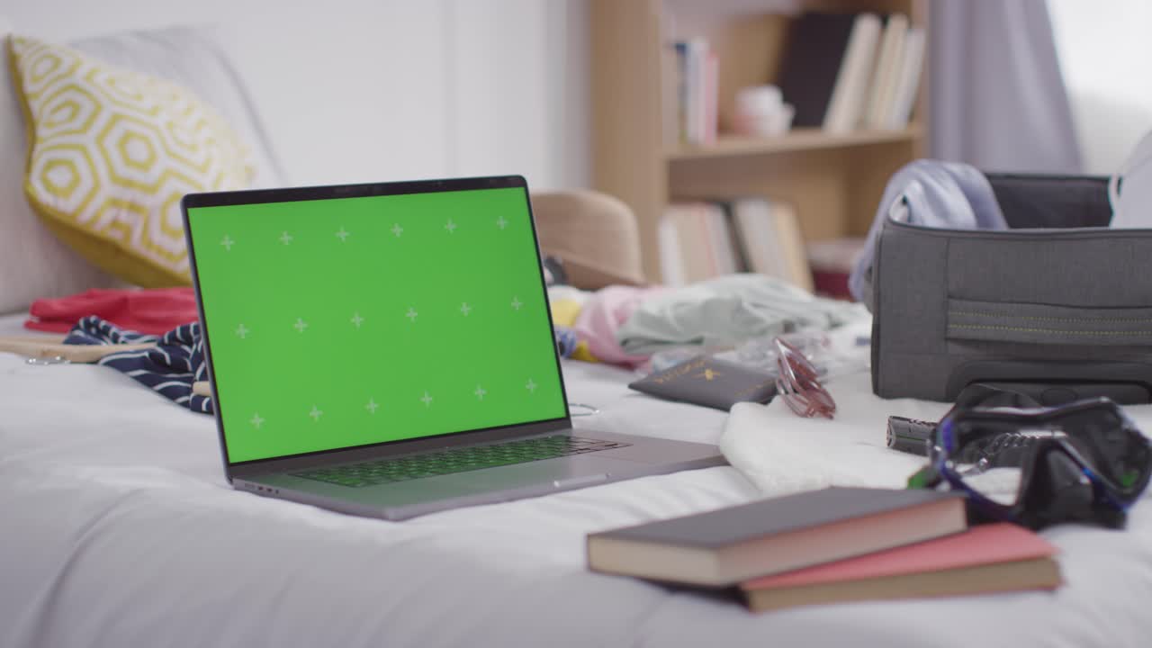 여름 휴가를 위해 집에서 침대 위에 열린 수하물과 함께 녹색 화면 노트북