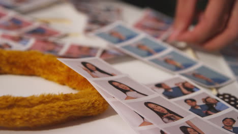 Close-Up-Of-A-Group-Of-Friends-Having-Fun-Looking-At-Prints-From-Photo-Booth-With-Props-2