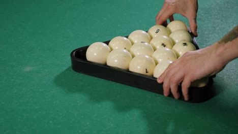 triangle of billiard balls. a man getting ready to start a game of billiards.