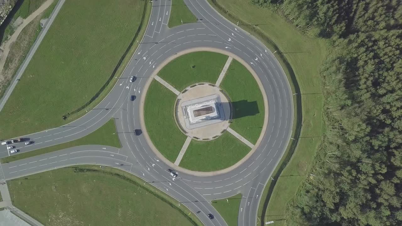 la cámara del dron gira alrededor de un anillo circular de tráfico en una avenida de la ciudad.