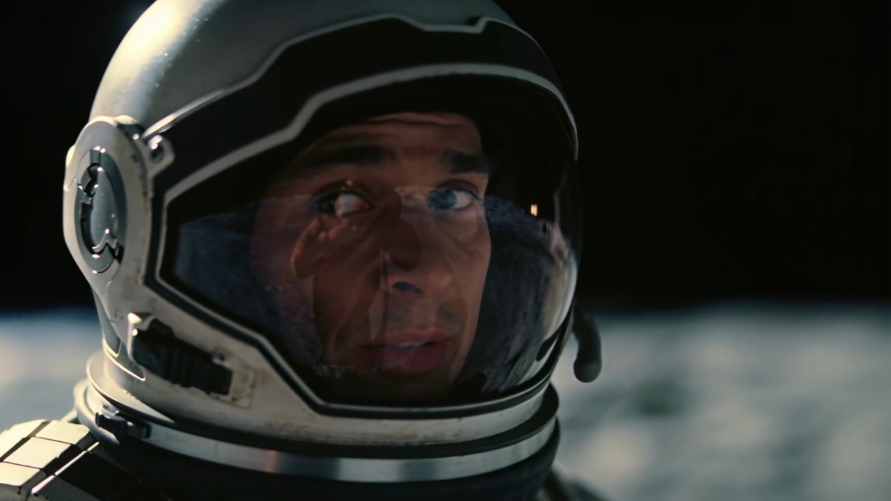 Astronauta con casco che scruta, alzando la mano guantata, spostando lo sguardo sulla superficie rocciosa, rispondendo alla radio.
